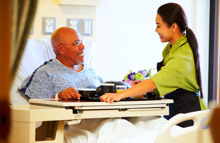 caregiver serving a meal to senior man