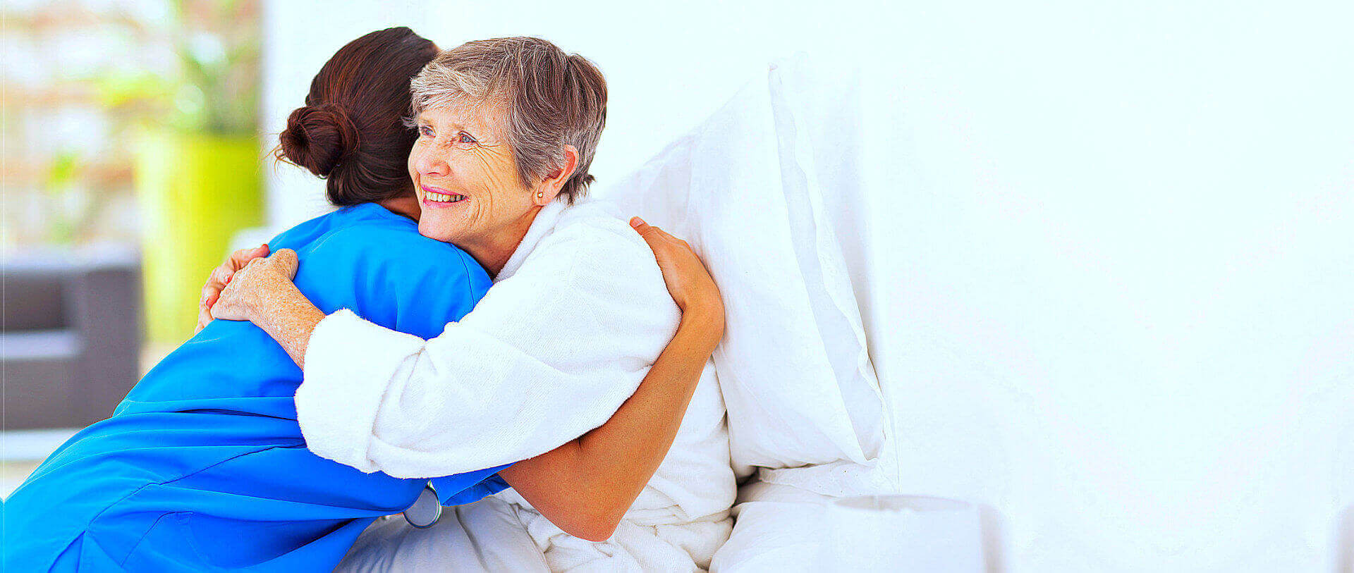 nurse and senior woman are hugging together while smiling