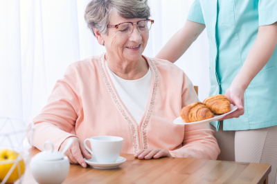 caregiver serving breakfast to a senior woman